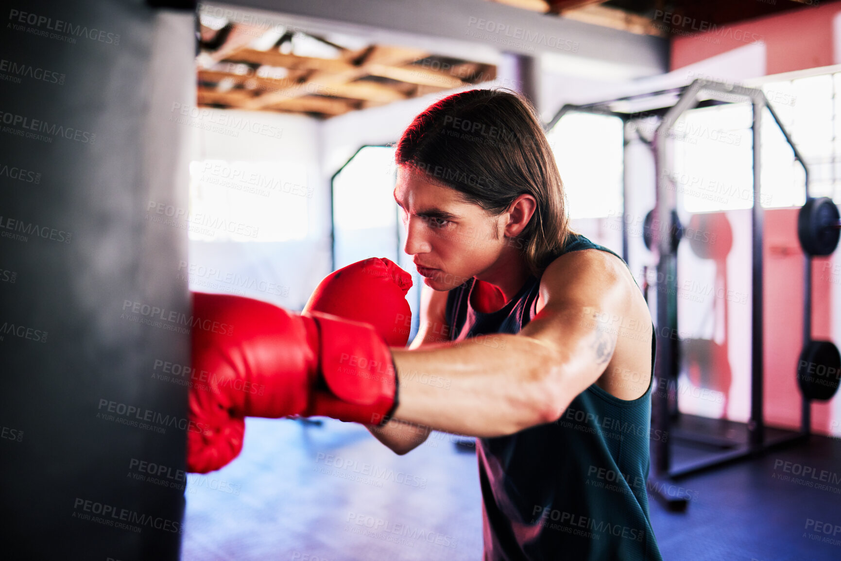 Buy stock photo Punching bag, man and boxing in gym for exercise, workout or training for fight. Boxer, sports and serious fitness athlete punch for challenge, competition or exercising body for martial arts power.