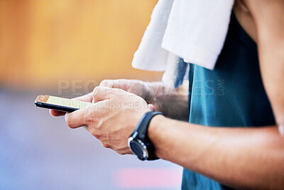 Closeup of one fit caucasian man using a cellphone while taking a break from training in a gym. Hands of a guy texting and browsing fitness apps online while checking social media during a rest from workout