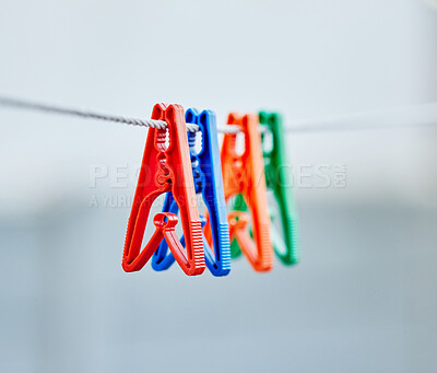 Closeup of a group of clothing pegs on a washing line outside during the day. Concept of plastic laundry pegs. Macro view of four cloth pegs hanging on a drying line outdoors after domestic chores