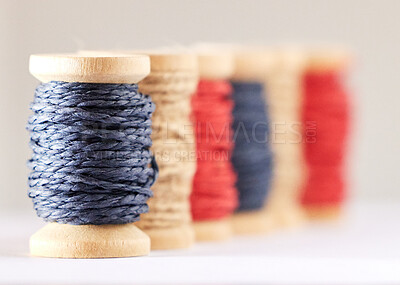Closeup of colourful threads twisted on wooden spools. Twine coiled around a roll for sewing, craftwork or embroidery. Yarn material used in the fashion and textile industry or for handmade crafts