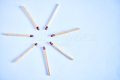 Seven matchsticks arranged in a circle in studio isolated against a blue background. All it takes is a spark to ignite and burst into flames. All you need to start a fire to keep warm during winter