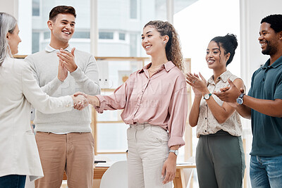 Happy businesswomen shaking hands while their coworkers clap hands in support in a meeting at work. Business professionals greeting and making deals with each other. Boss hiring an employee