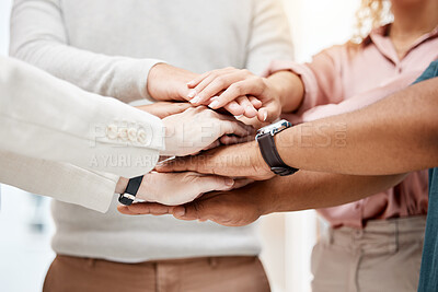 Closeup of a group of businesspeople stacking their hands together in an office at work. Business professionals having fun standing with their hands piled for support and motivation during a meeting