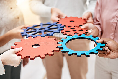 Buy stock photo Group of five businesspeople holding and fitting gears together in an office at work. Business professionals having fun connected gear pieces during a meeting