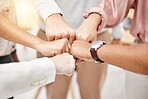 Group of five businesspeople giving each other a fist bump in support together in an office at work. Business professionals having fun standing with their fists joined for motivation during a meeting