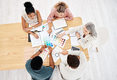 Group of five diverse businesspeople having a meeting at a table in an office from above. Serious business professionals talking while going through paper and reports together work