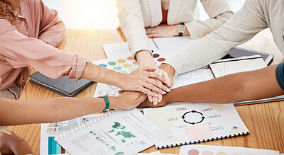 Group of businesspeople having a meeting at a table in an office. Business professionals joining their hands in support at work. Employees stacking their hands in motivation