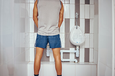 Back of a squash player urinating in his gym bathroom. Behind a fit man taking a break to urinate. Athletic man taking a break from his match to urinate in his gym toilet