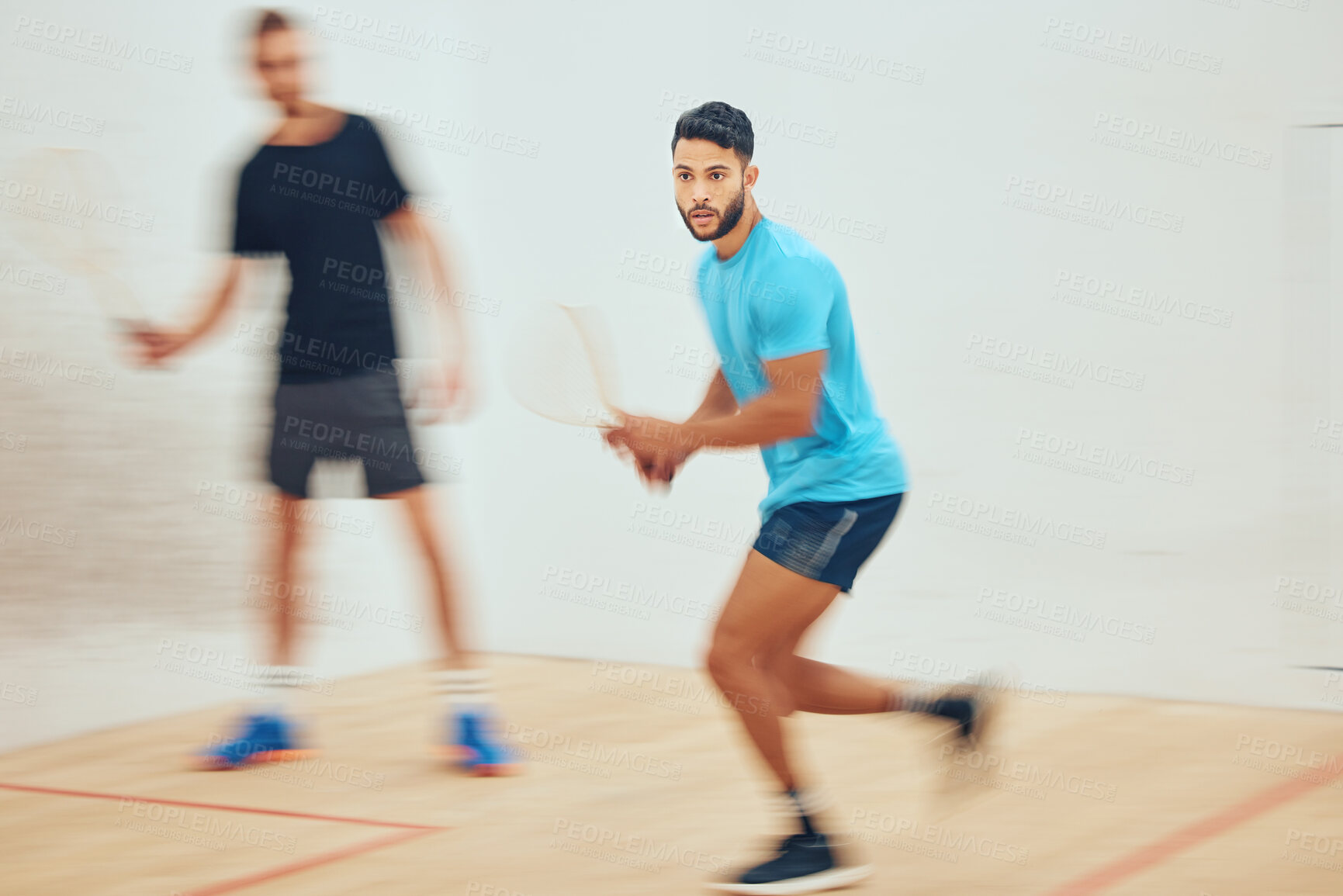 Buy stock photo Two athletic squash players playing a game on a court with copyspace. Fit active caucasian and mixed race male athletes competing and training together in sports centre. Healthy cardio and motion blur