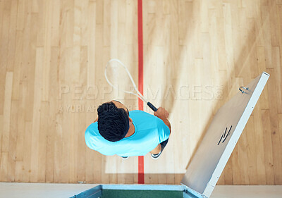 Above view of unknown athletic squash player standing alone before playing on court. Fit active mixed race athlete getting ready to practice and train for a game in sports centre. Hispanic sporty man