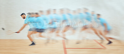 Young athletic squash player running while playing court game with motion blur. Fit active mixed race athlete moving with speed in training practice to hit a ball in sports centre. Sporty hispanic man