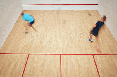 Above view of two athletic squash players playing a game on a court. Fit active caucasian and mixed race male athletes competing and training together in sports centre. Healthy cardio and motion blur