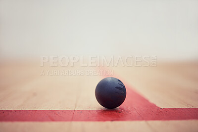 Closeup of one squash ball on wooden floor in empty court in sports centre with copyspace. Zoom equipment arranged on t position in sporty arena with nobody before championship game and competition