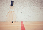 Group of squash equipment and gear on wooden floor in empty court in sports centre with copyspace. Two rackets and ball arranged in sporty arena with nobody before championship game and competition