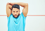 Portrait of squash player stretching and looking focused before playing court game with copyspace. Fit active hispanic athlete standing alone and getting ready for training practice in sports centre