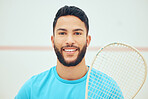 Portrait of squash player smiling and holding racket before playing court game with copyspace. Happy fit active hispanic athlete standing alone and getting ready for training practice in sports centre
