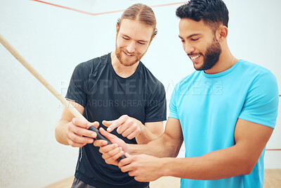 Buy stock photo Young athletic squash player showing friend how to hold and grip racket before playing game on court. Two fit active mixed race and caucasian athletes learning in training practice at sports centre