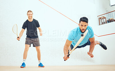 Two athletic squash players playing match during competitive court game. Fit active mixed race and caucasian athlete competing during training challenge in sports centre. Sporty men in championship