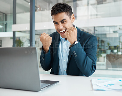 Young mixed race businessman cheering with passion while working on a laptop alone at work. One hispanic businessperson smiling and celebrating victory working at a desk in an office