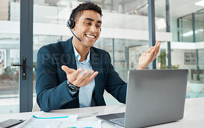 Young happy mixed race male call center agent answering calls while wearing a headset and working on a laptop alone at work. One hispanic businessperson smiling while working at a desk in an office