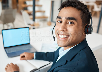 Buy stock photo Portrait of a young happy mixed race businessman working on a laptop alone at work. One hispanic businessperson smiling while working at a desk in an office