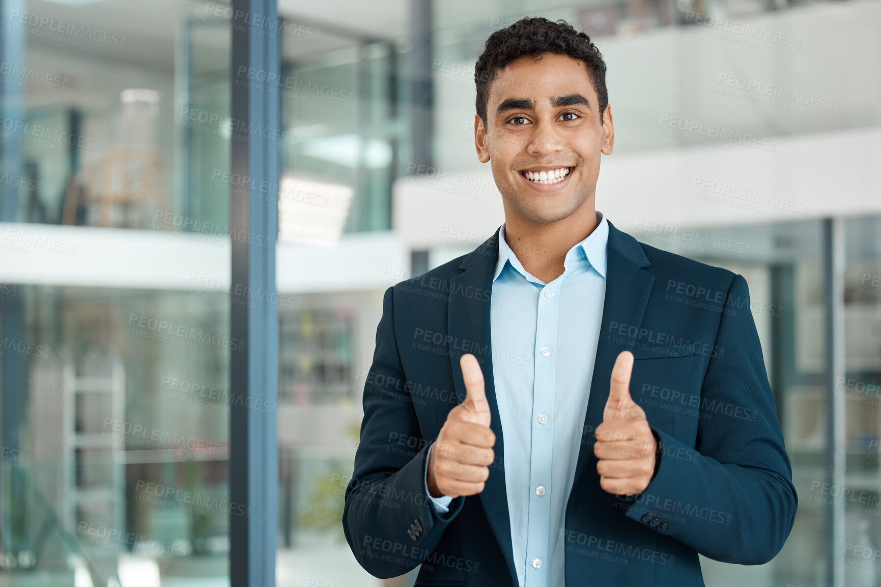 Buy stock photo Young happy mixed race businessman showing two thumbs up standing alone at work. One pleased and content hispanic businessperson smiling while showing support with two thumbs up in an office