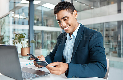 Young happy mixed race businessman holding and using a credit card and phone alone at work. One hispanic male businessperson smiling while making an online payment with his debit card and cellphone
