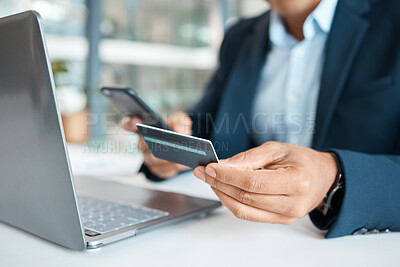 Closeup of a mixed race businessman holding and using a credit card and phone alone at work. One hispanic male businessperson making an online payment with his debit card and smartphone