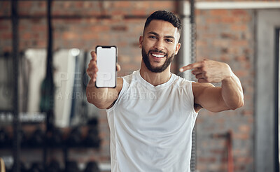 Fit young man showing his smartphone screen. Muscular bodybuilder using a smartphone in the gym. Young athlete using an online app on his cellphone. Athletic man using his mobile device