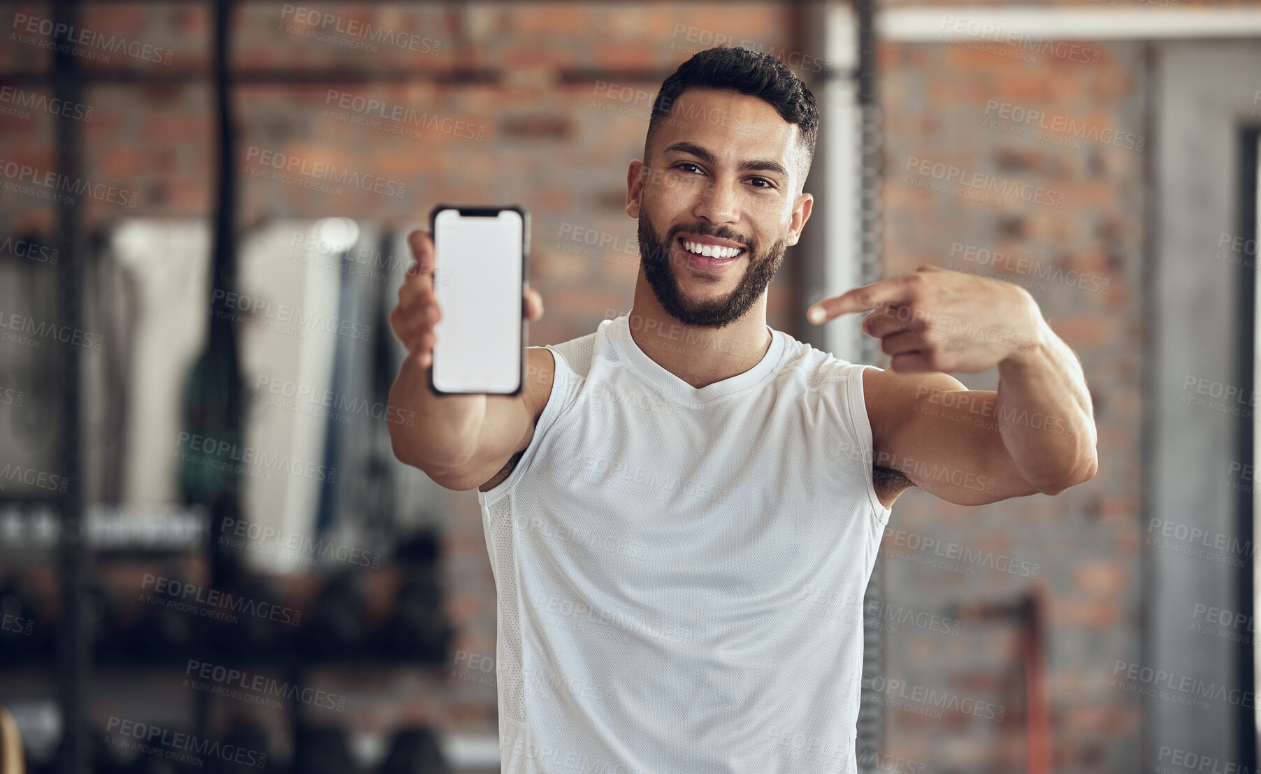 Buy stock photo Fit young man showing his smartphone screen. Muscular bodybuilder using a smartphone in the gym. Young athlete using an online app on his cellphone. Athletic man using his mobile device