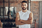 Portrait of bodybuilder with attitude in the gym. Young bodybuilder with arms crossed in the gym. Cool, fit man standing in the gym. Healthy athlete taking a break from training in the gym