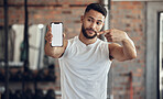 Athlete making a facial expression holding his phone. Fit young man showing his mobile device screen in the gym. Handsome young man using his cellphone in the gym. Bodybuilder pointing to his phone