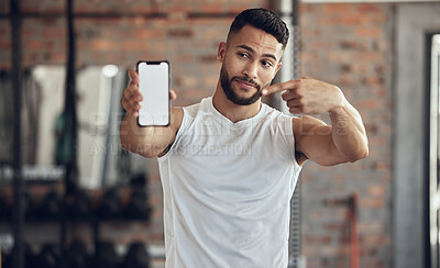 Buy stock photo Athlete making a facial expression holding his phone. Fit young man showing his mobile device screen in the gym. Handsome young man using his cellphone in the gym. Bodybuilder pointing to his phone
