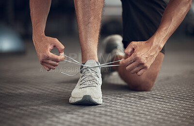 Buy stock photo Closeup of athlete tying his shoelaces in the gym. Hands of fit man getting ready with his gym shoes. Bodybuilder ready to workout. Fit athlete tying the laces of a sport sneaker