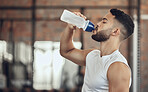 Man taking a break from exercise to hydrate.Young man drinking water from a bottle during exercise. Active fit man drinking water during a workout. Bodybuilder taking a break from exercise