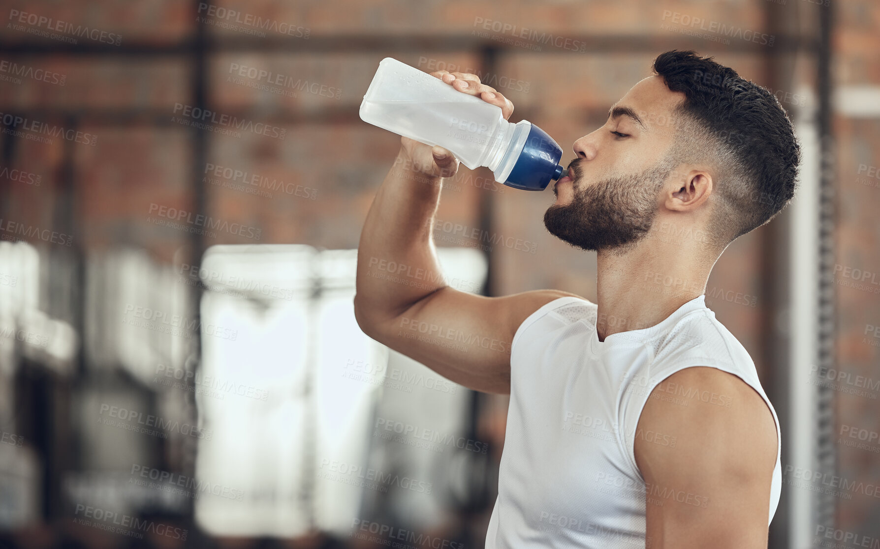 Buy stock photo Man taking a break from exercise to hydrate.Young man drinking water from a bottle during exercise. Active fit man drinking water during a workout. Bodybuilder taking a break from exercise
