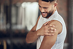 Young athlete experiencing arm pain. Bodybuilder with a bicep cramp in the gym. Fit young man with shoulder pain in the gym. Young athlete with a sore, stiff arm in the gym.