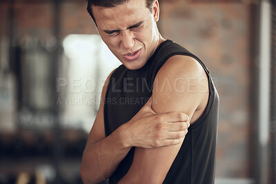 Buy stock photo Young athlete with a stiff arm in the gym. Bodybuilder feeling bicep pain in the arm. Young fit man with a sore arm in the gym. Active athlete with a hurt arm injury. Fit man in discomfort in the gym