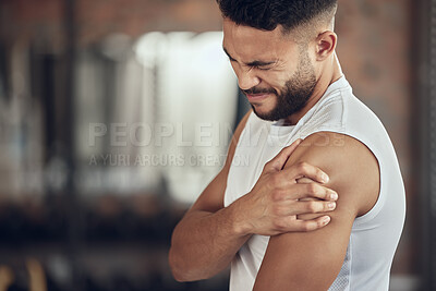 Buy stock photo Young man with shoulder pain in the gym. Fit athlete touching his arm in pain. Active bodybuilder with a bicep cramp in the gym. Strong man with arm ache in the gym. Man with muscle pain in the gym