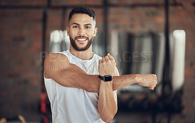 Buy stock photo Portrait of an athlete stretching his shoulder. Young man doing an arm warmup before a workout. Bodybuilder getting ready to exercise in the gym. Confident fit man stretching his arm before a workout