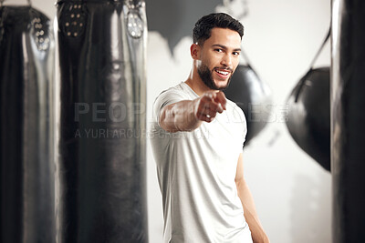 Buy stock photo Portrait of one fit young hispanic man pointing forward with his finger while exercising in a gym. Happy mixed race instructor motivating and encouraging you to workout in a fitness centre