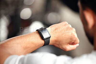 Closeup of one mixed race man checking his digital wristwatch with blank display screen while training in a gym. Guy from above wearing fitness tracker on arm to monitor progress, heart rate and calories burned during exercise in a fitness centre