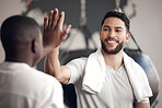 One confident young hispanic man giving a high five to his friend while exercising in a gym. Happy mixed race guy staying motivated while celebrating the end of a successful training workout with an instructor in a fitness centre
