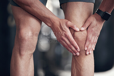 Buy stock photo Closeup of one mixed race man holding his sore knee while exercising in a gym. Guy suffering with painful leg injury from fractured joint and inflamed muscles during workout. Struggling with stiff body cramps causing discomfort and strain