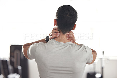 Buy stock photo One mixed race man from behind holding his sore neck while exercising in a gym. Guy suffering with painful injury from fractured joint and inflamed muscles during workout. Struggling with stiff body cramps causing discomfort and strain