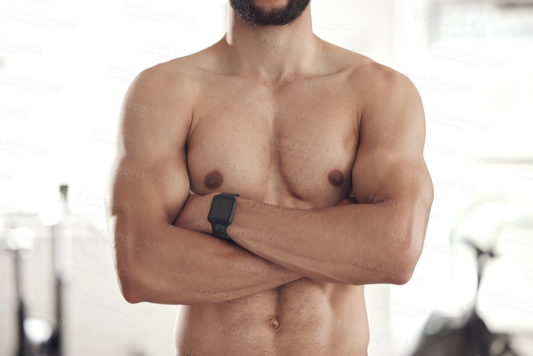 Closeup of one fit topless mixed race man with big strong muscles from  regular exercise standing with arms crossed in a gym. Bodybuilder with  toned and sexy physique. Brawny athlete proud of