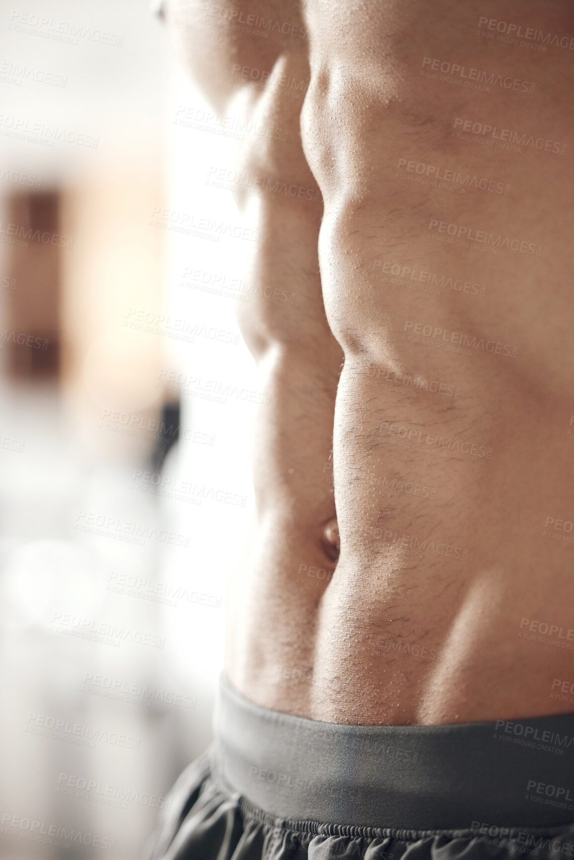 Closeup of one fit topless mixed race man with muscular hard six pack abs  from regular exercise in a gym. Bodybuilder with toned physique and sexy  torso. Brawny athlete proud of physical