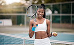 Young girl holding her tennis racket and ball on the court. Portrait of an african american woman ready for her tennis practice. Confident young tennis player on the court