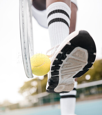 Closeup of tennis player holding a ball and racket against their shoe. hands of a tennis player standing on the court from below. Tennis player wearing a sport sneaker ready for a match