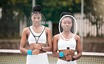 Serious tennis players holding their rackets. Portrait of young tennis players covering their faces with rackets on the court. African american girls ready for a tennis match.